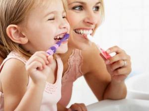 дівчинка чистить зубки з мамою